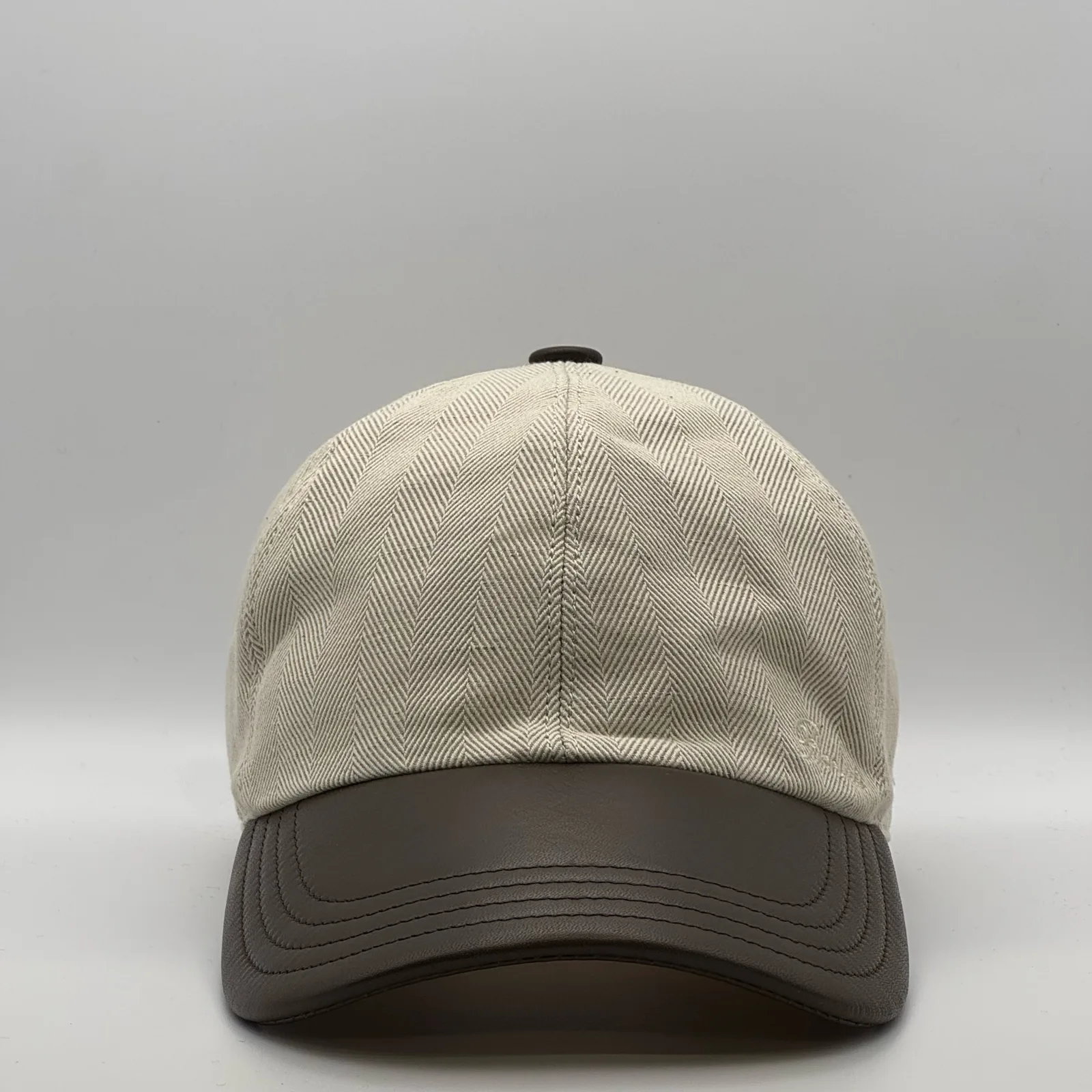 Berluti linen cap, front view in cream herringbone linen with a dark brown leather brim.