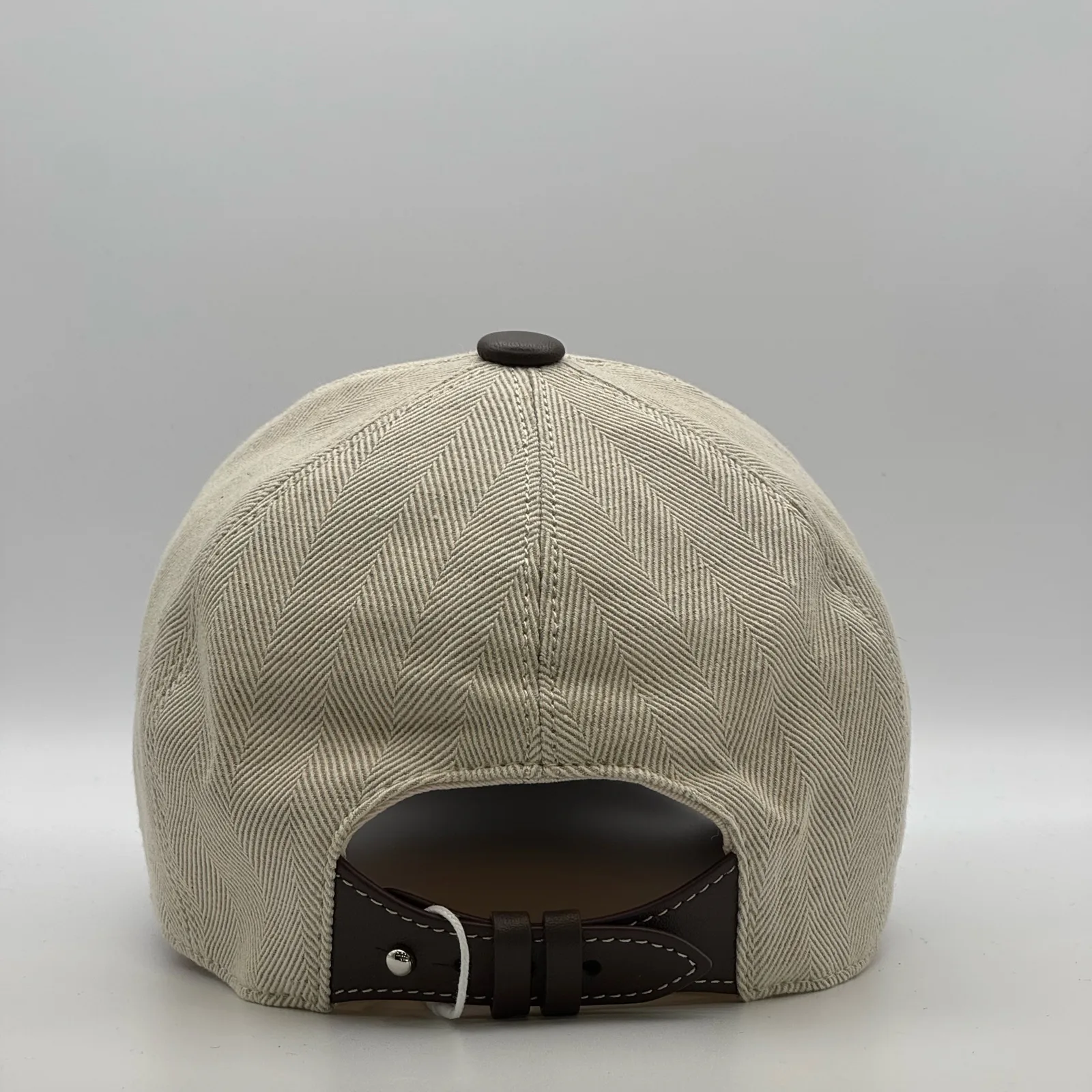 Berluti linen cap, back view showing the curved dark brown leather strap and buckle.