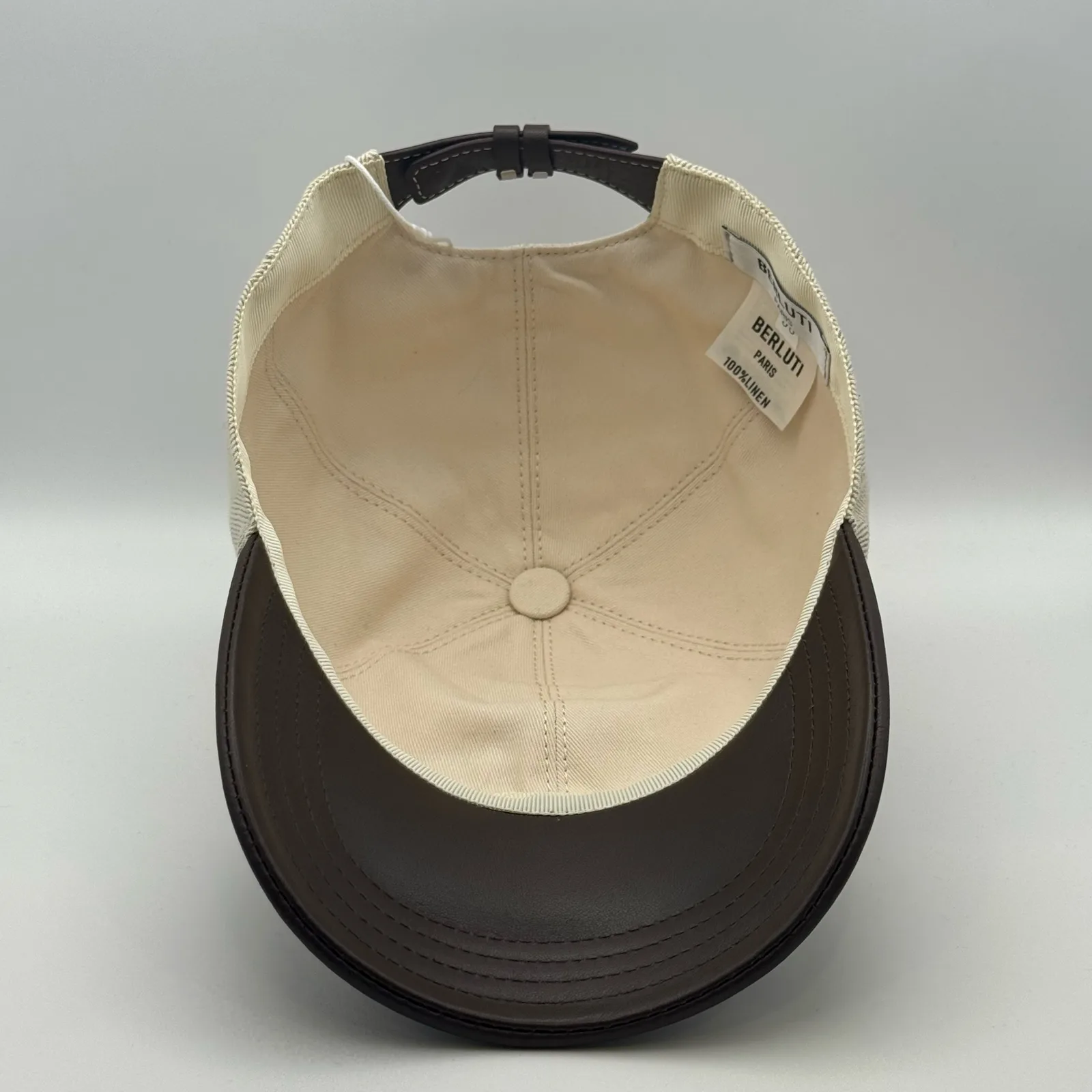 Berluti linen cap, underside view showing the cream interior lining and dark brown brim.