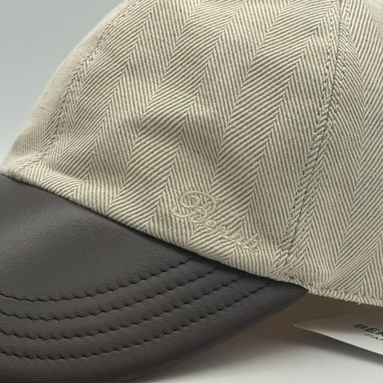 Close-up of the dark brown leather brim meeting the herringbone linen crown.