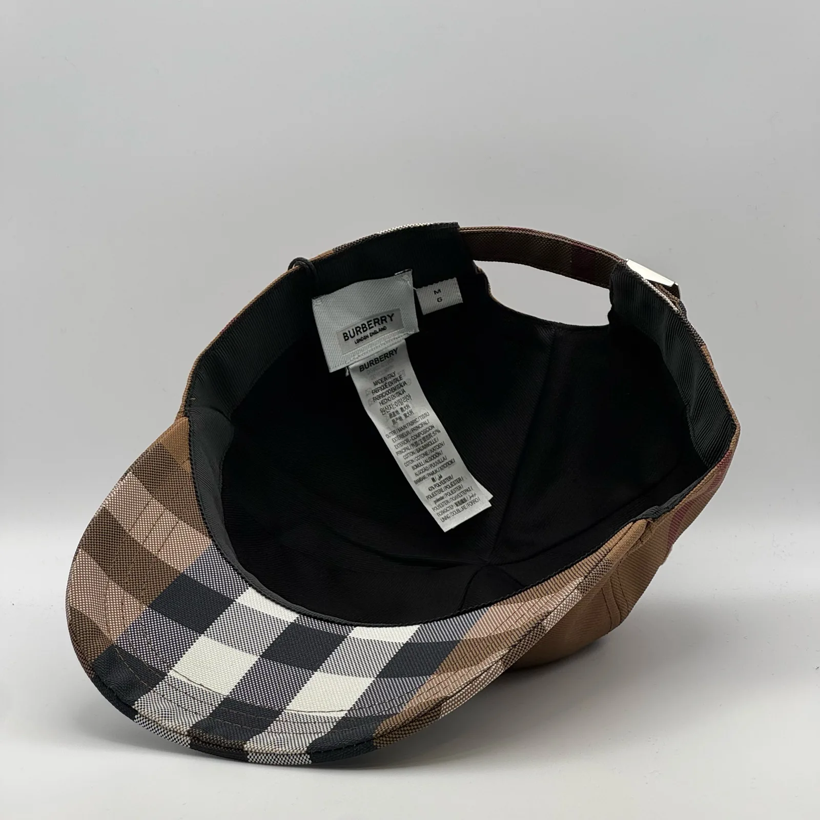 Underside of the brown check cap, brim lifted to show the interior.