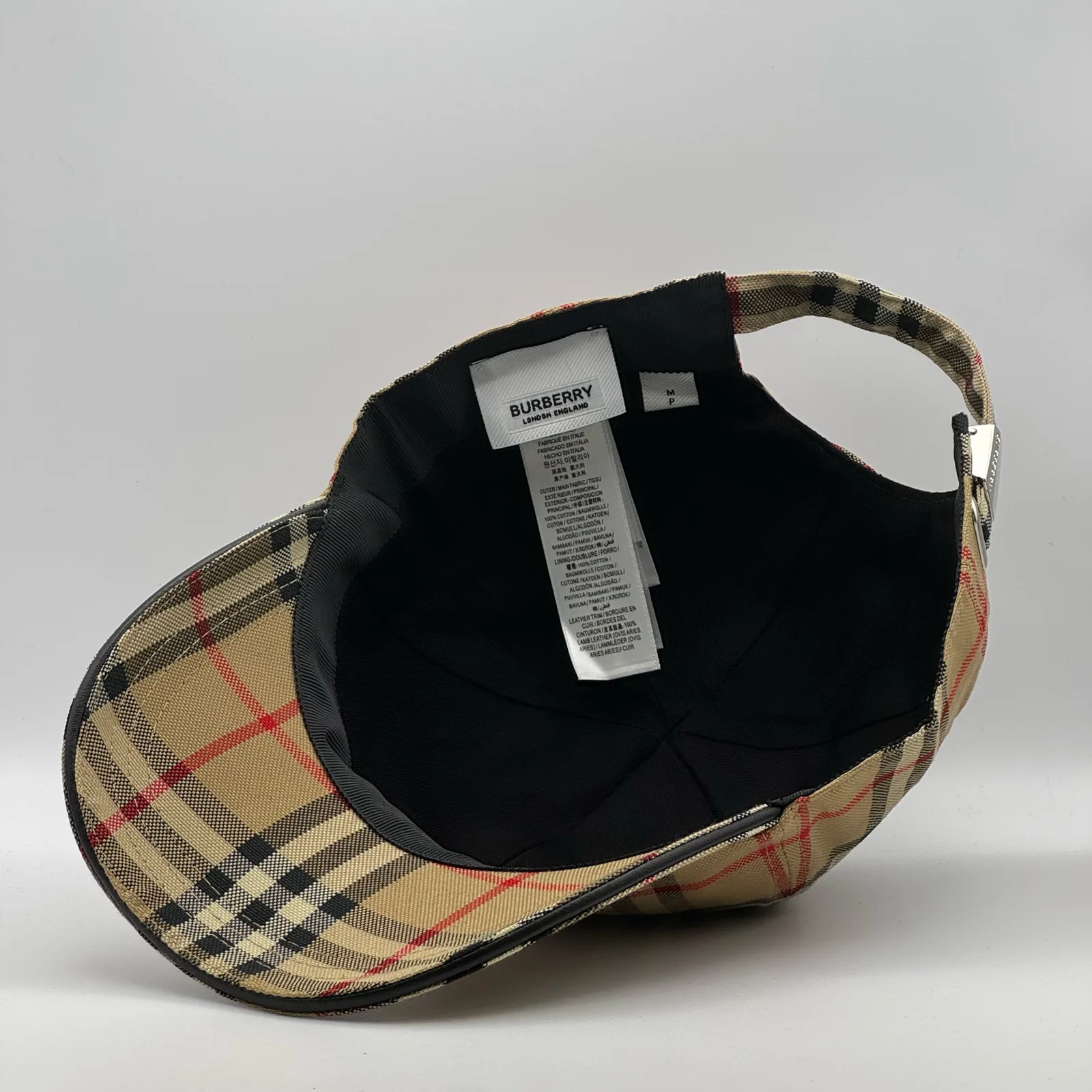 Underside of the archive beige check cap, brim lifted to show the interior and tag.