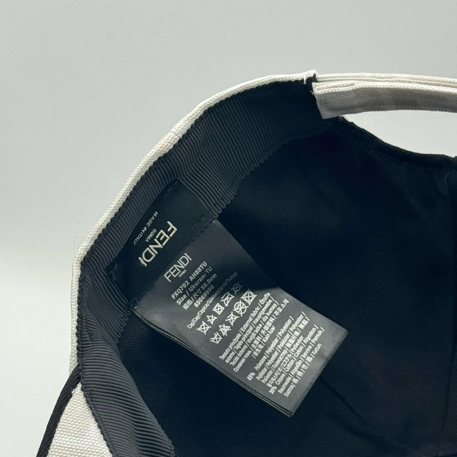 Close-up of the Fendi brand tag and care label inside the white FF cap.