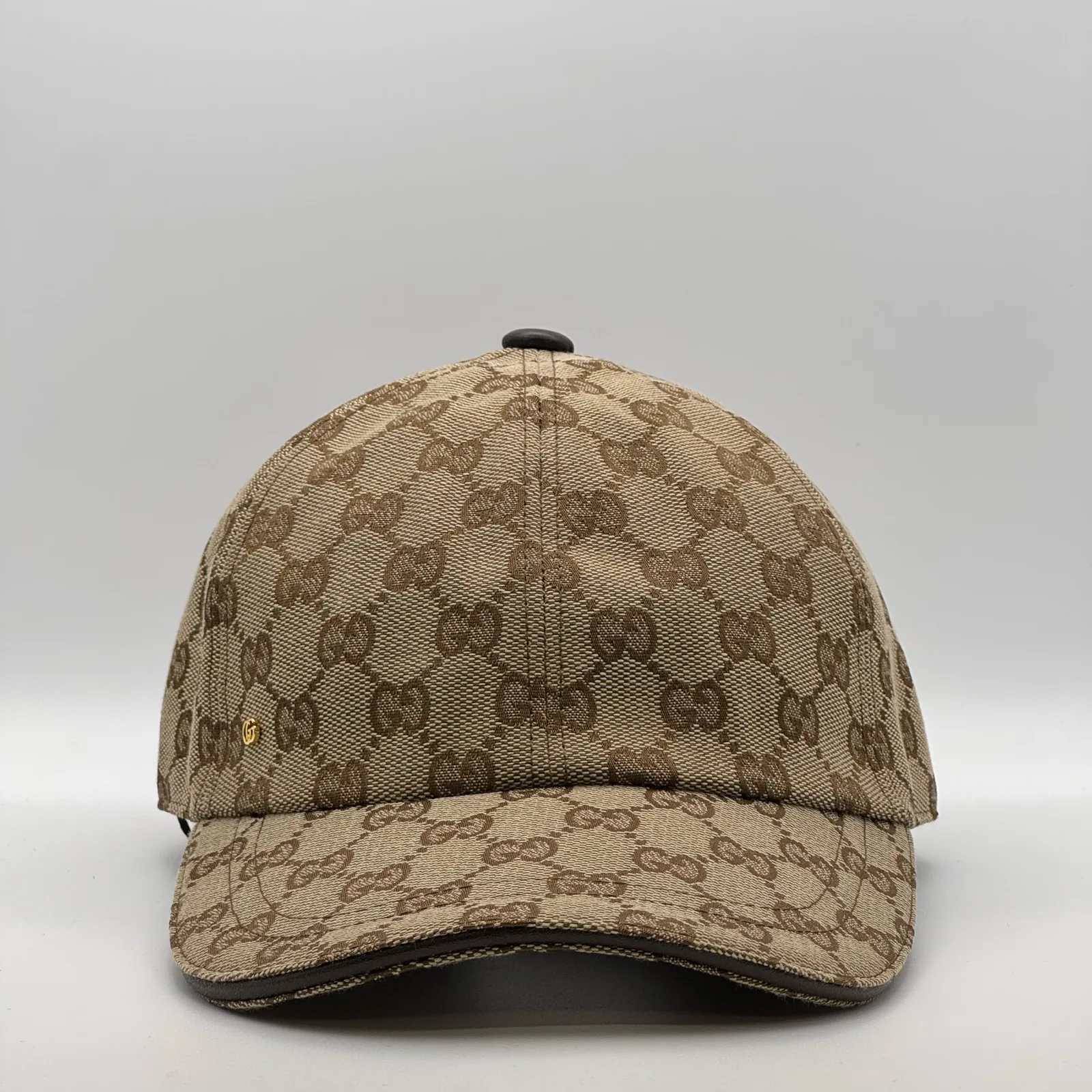 Beige GG canvas cap, front three-quarter view with tonal brown trim and leather brim
