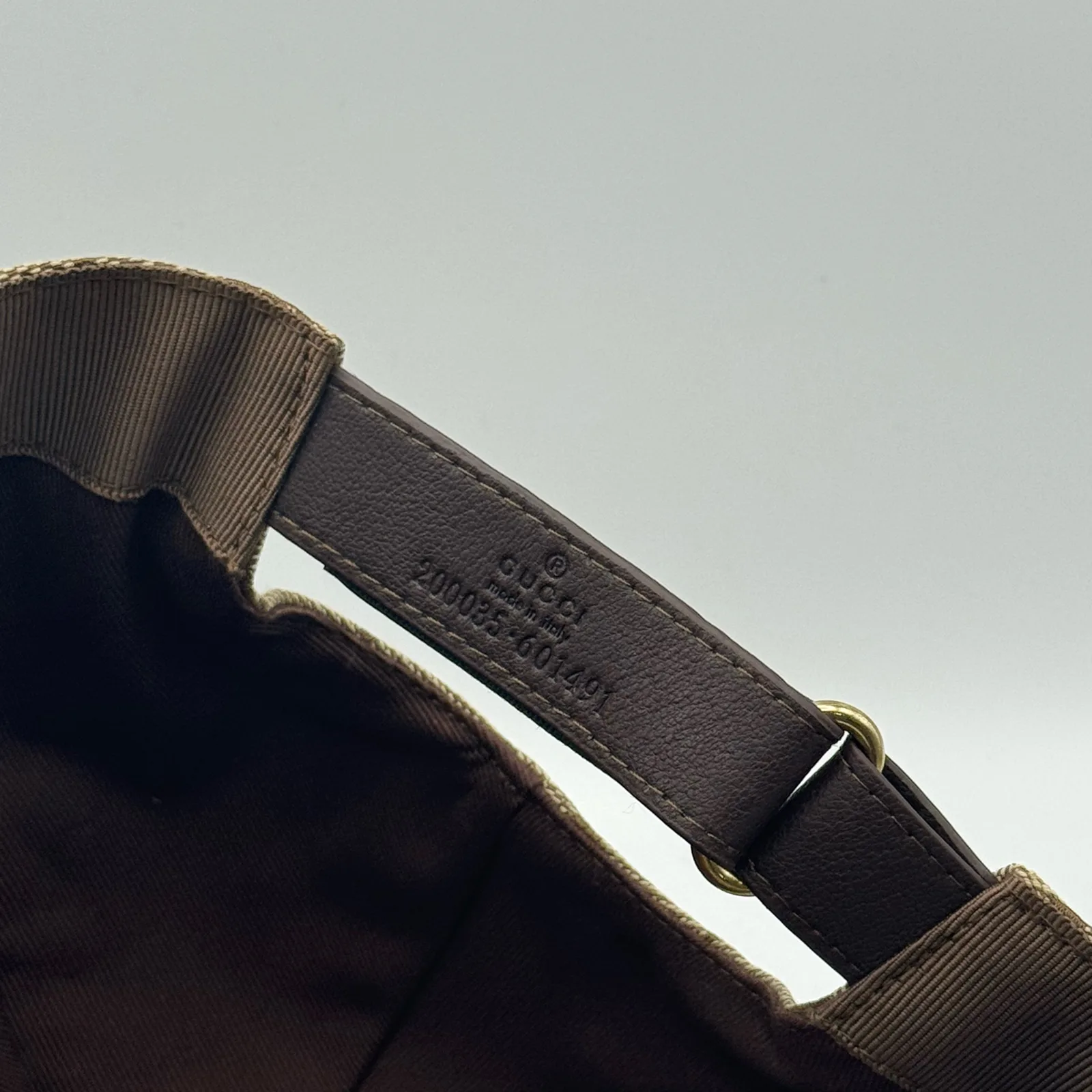 Beige GG canvas cap, close-up of the leather strap with debossed Gucci wordmark