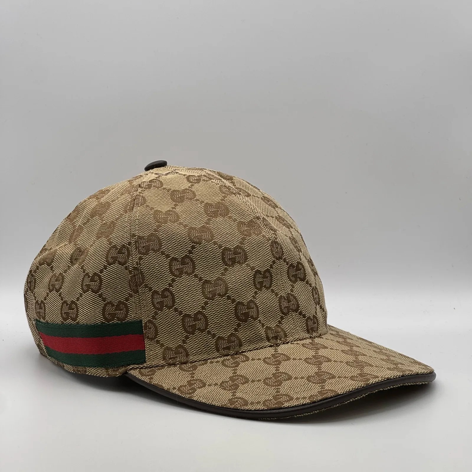 Beige GG canvas cap, side view showing the web stripe and dark brown leather brim