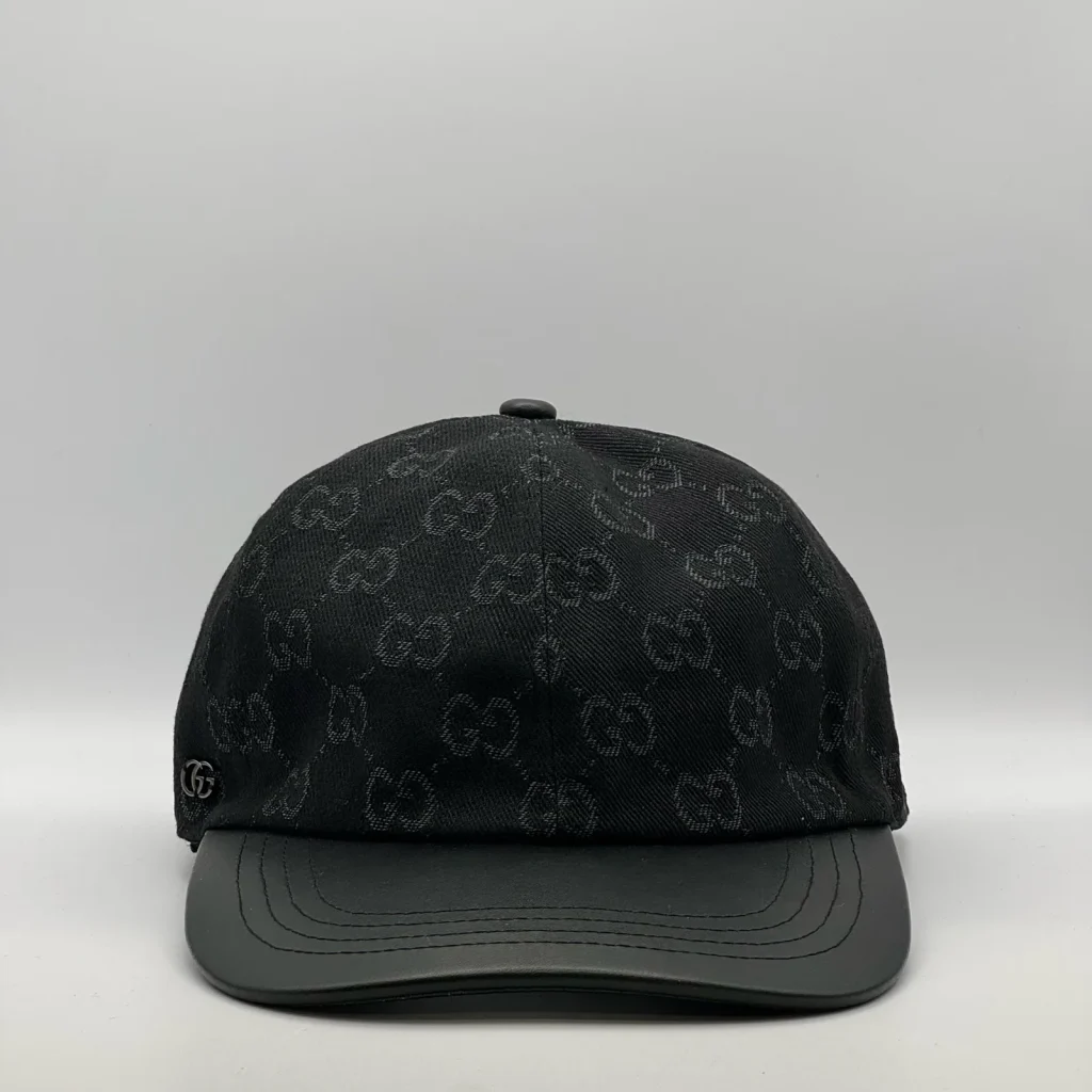 Black GG canvas cap, front three-quarter view with a smooth black leather brim