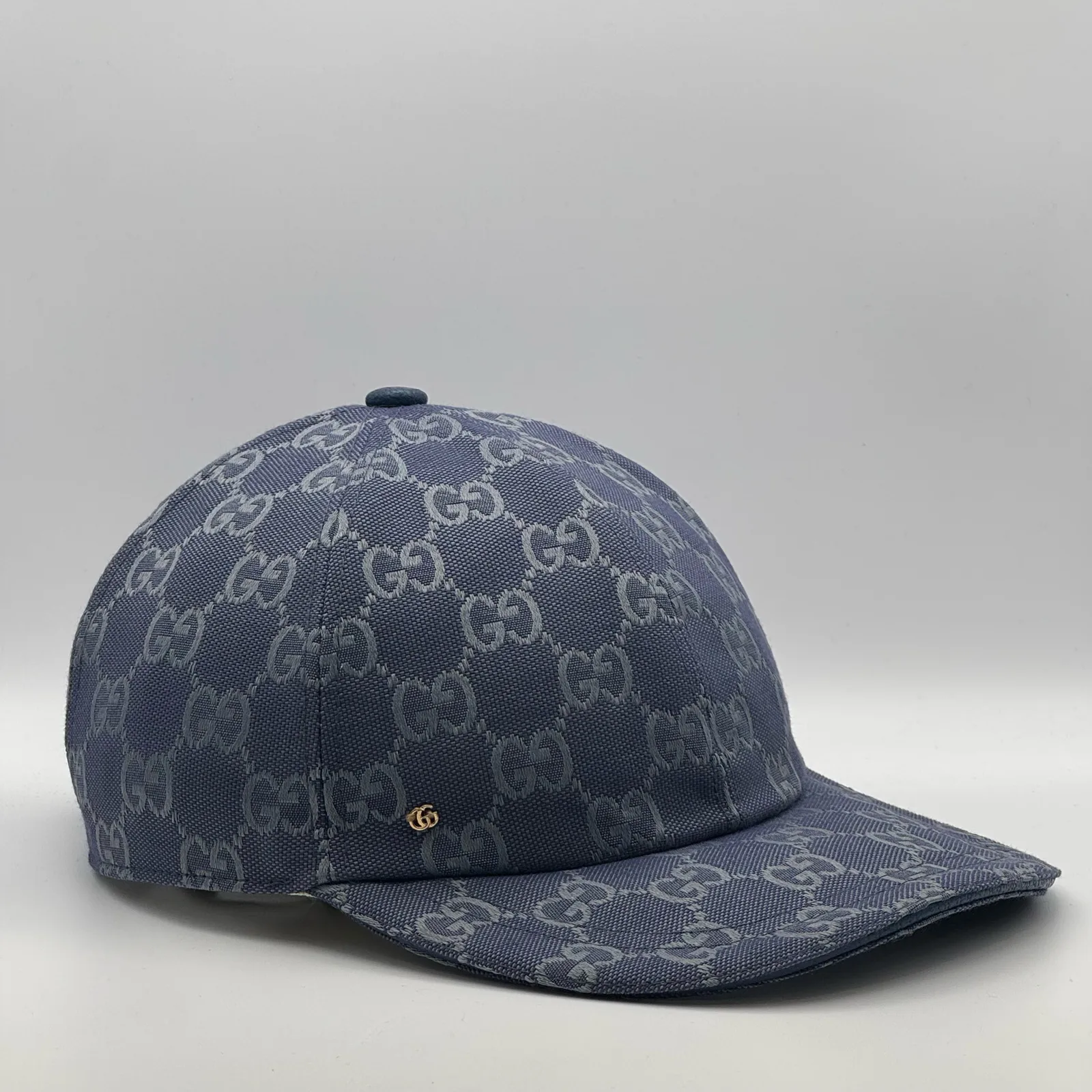 Denim blue GG canvas cap, side view showing the cream leather strap