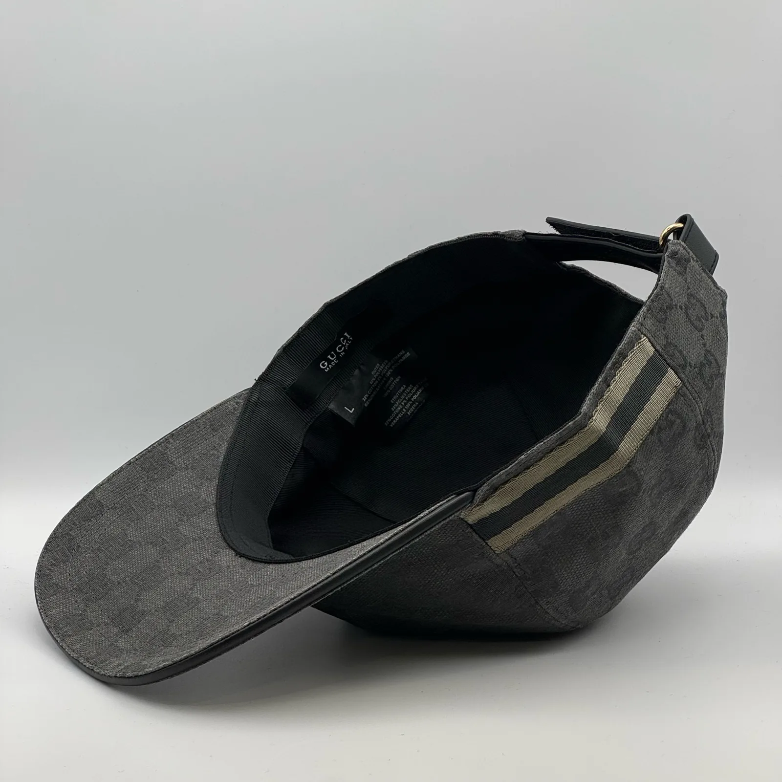 Charcoal grey GG canvas cap, brim lifted showing the web stripe and interior tag