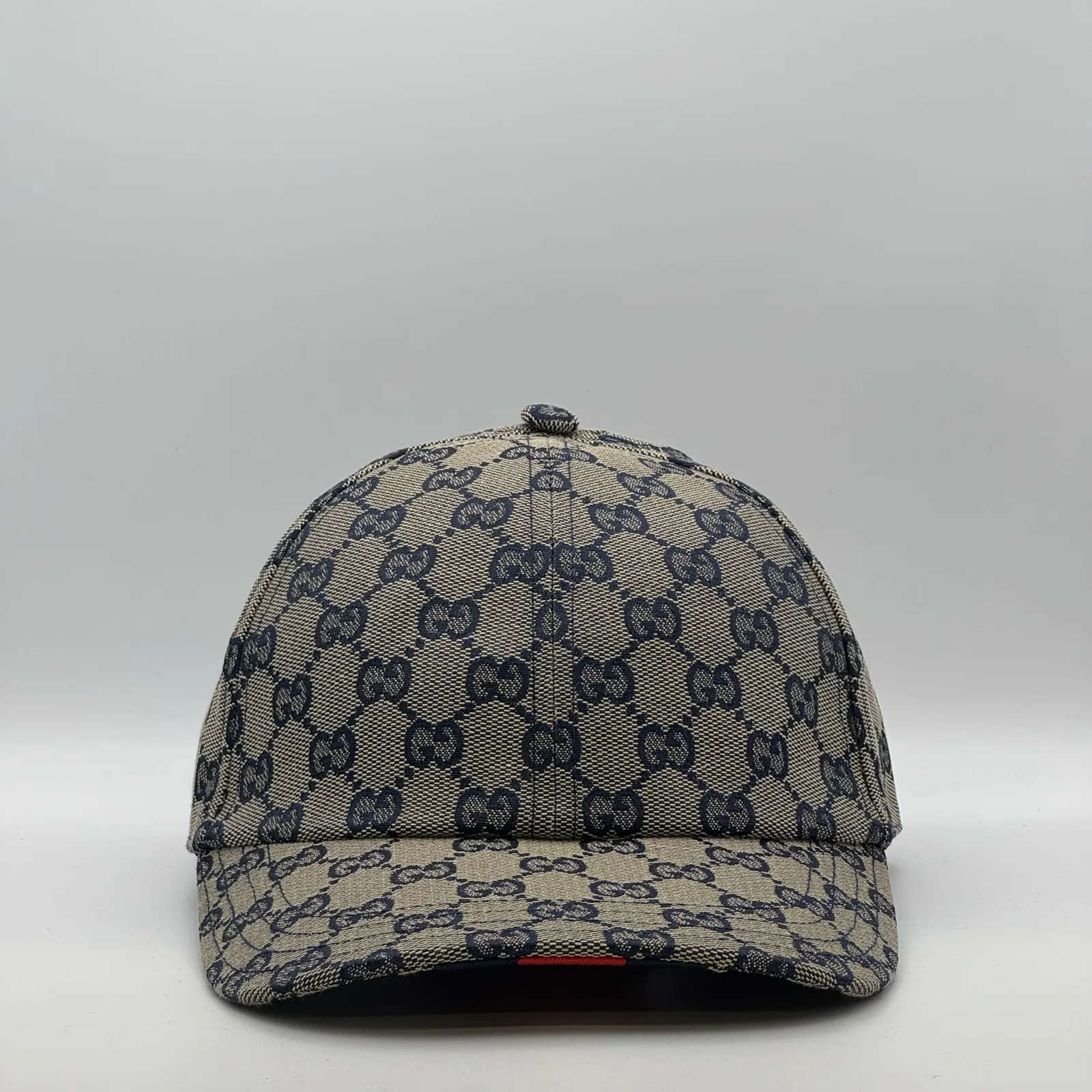 Navy and beige GG canvas cap, front three-quarter view with red web stripe trim