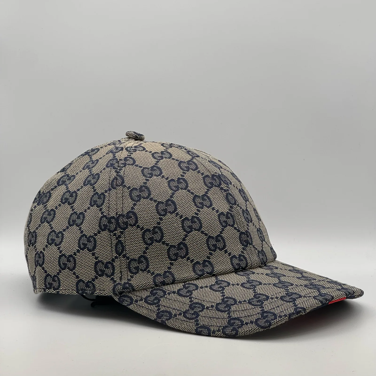 Navy and beige GG canvas cap, side view showing the black leather brim