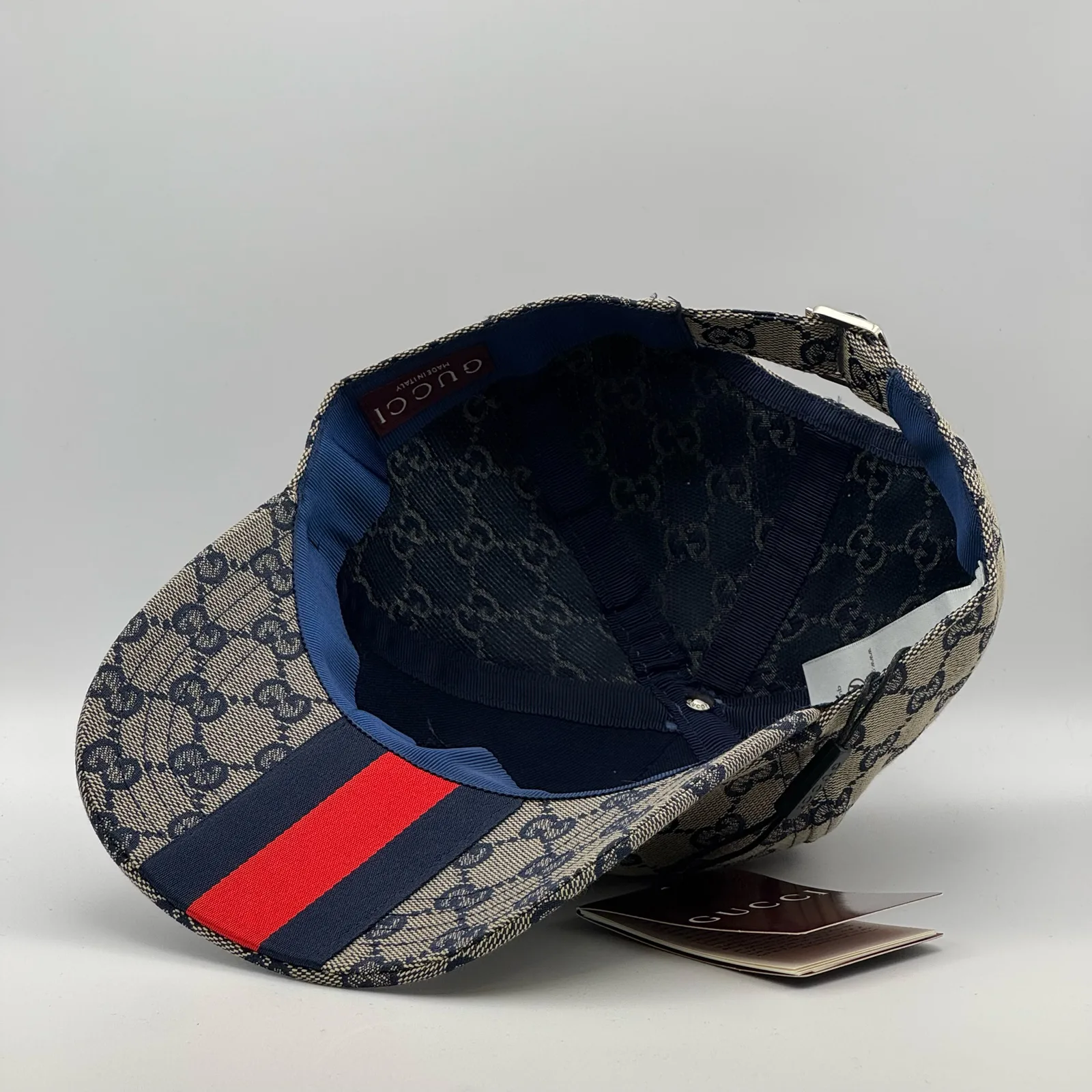 Navy and beige GG canvas cap, interior view with brand tag and booklet