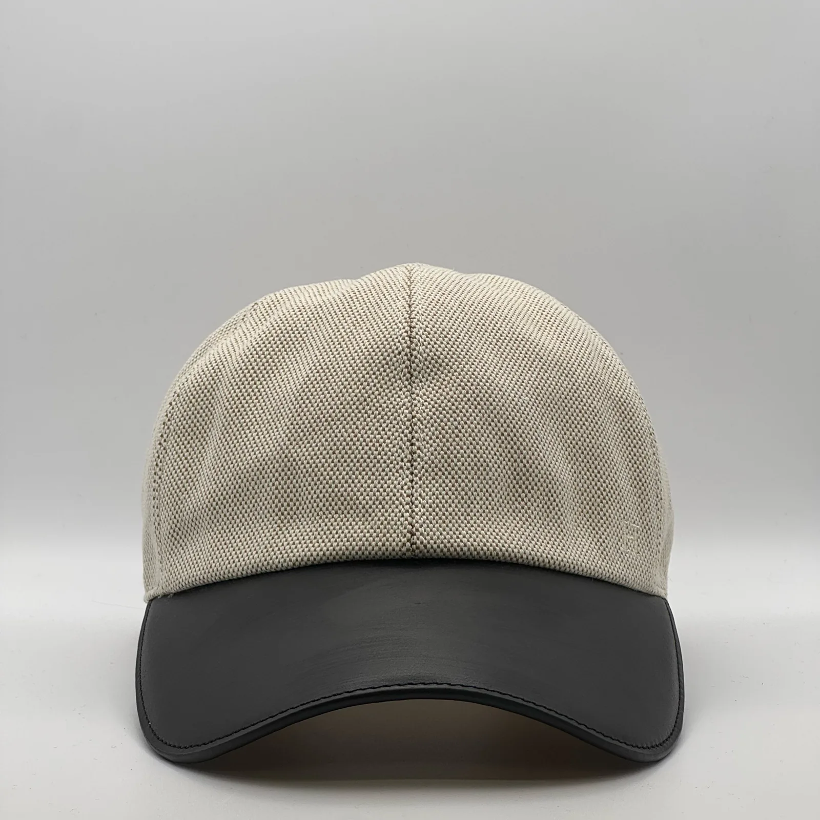 Hermès canvas cap, front view in oatmeal weave with a black leather brim.