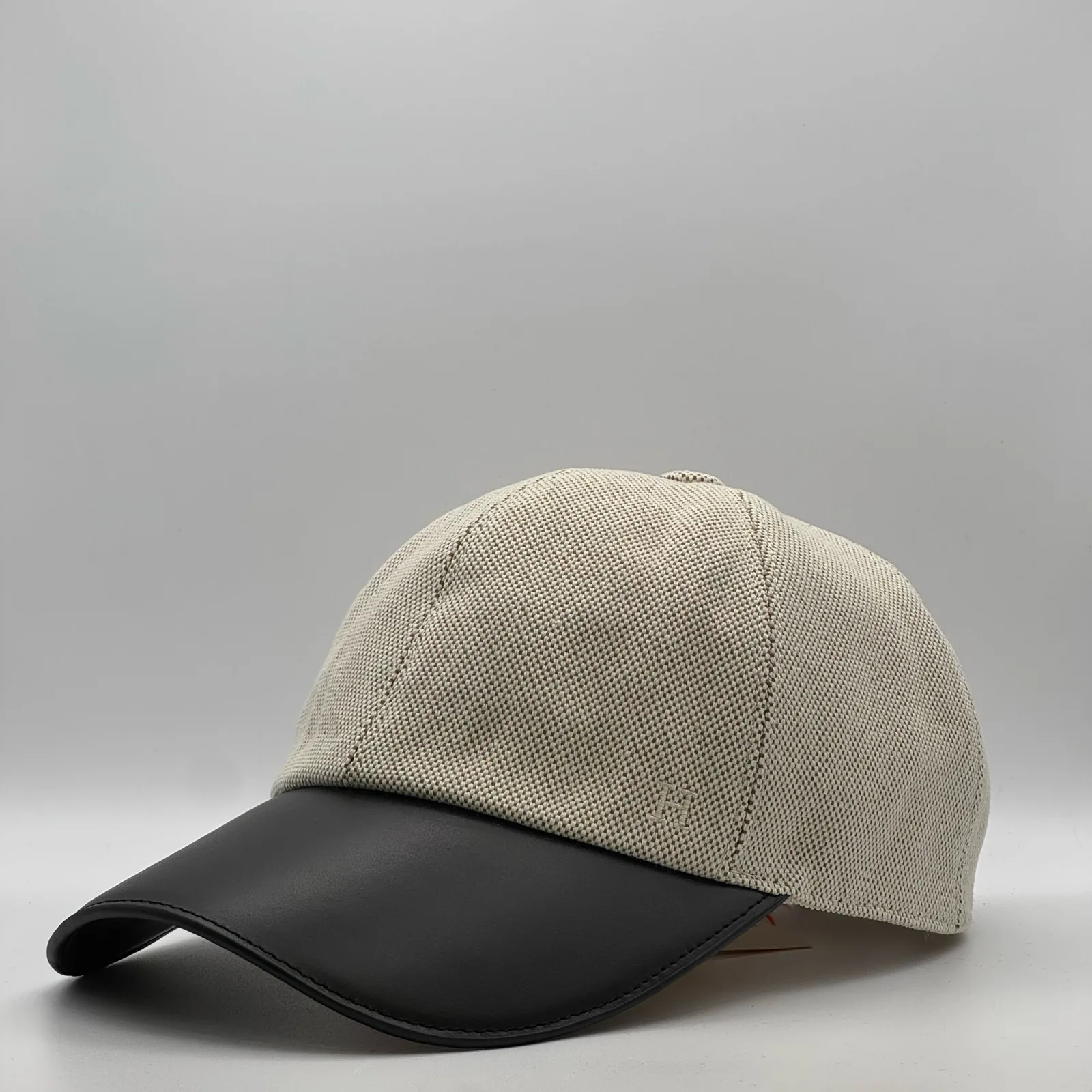 Hermès canvas cap, side profile in woven canvas with a black leather brim.
