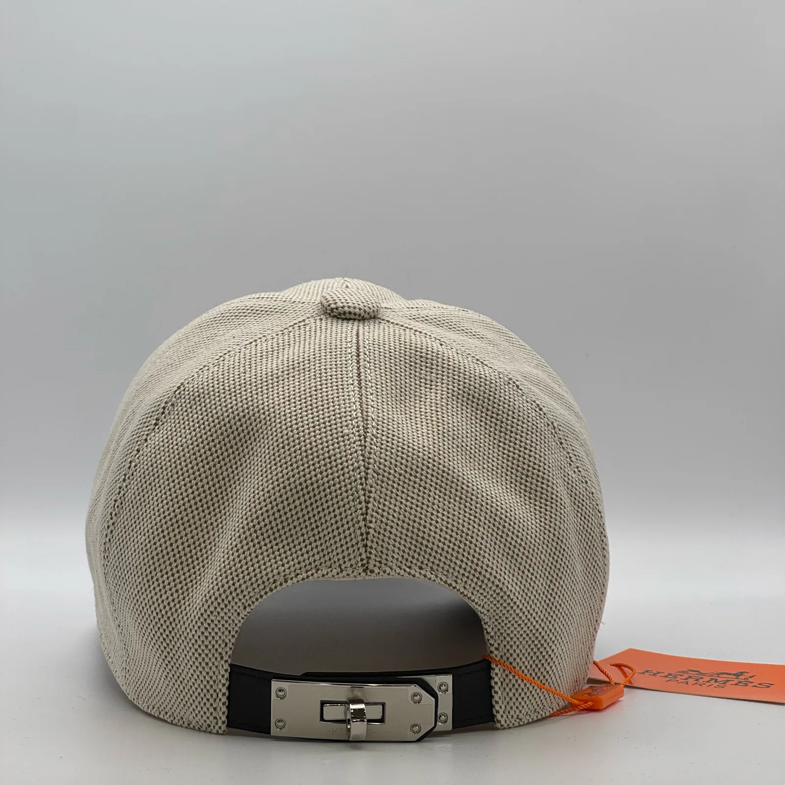Hermès canvas cap, back view showing the black leather strap and metal buckle closure.