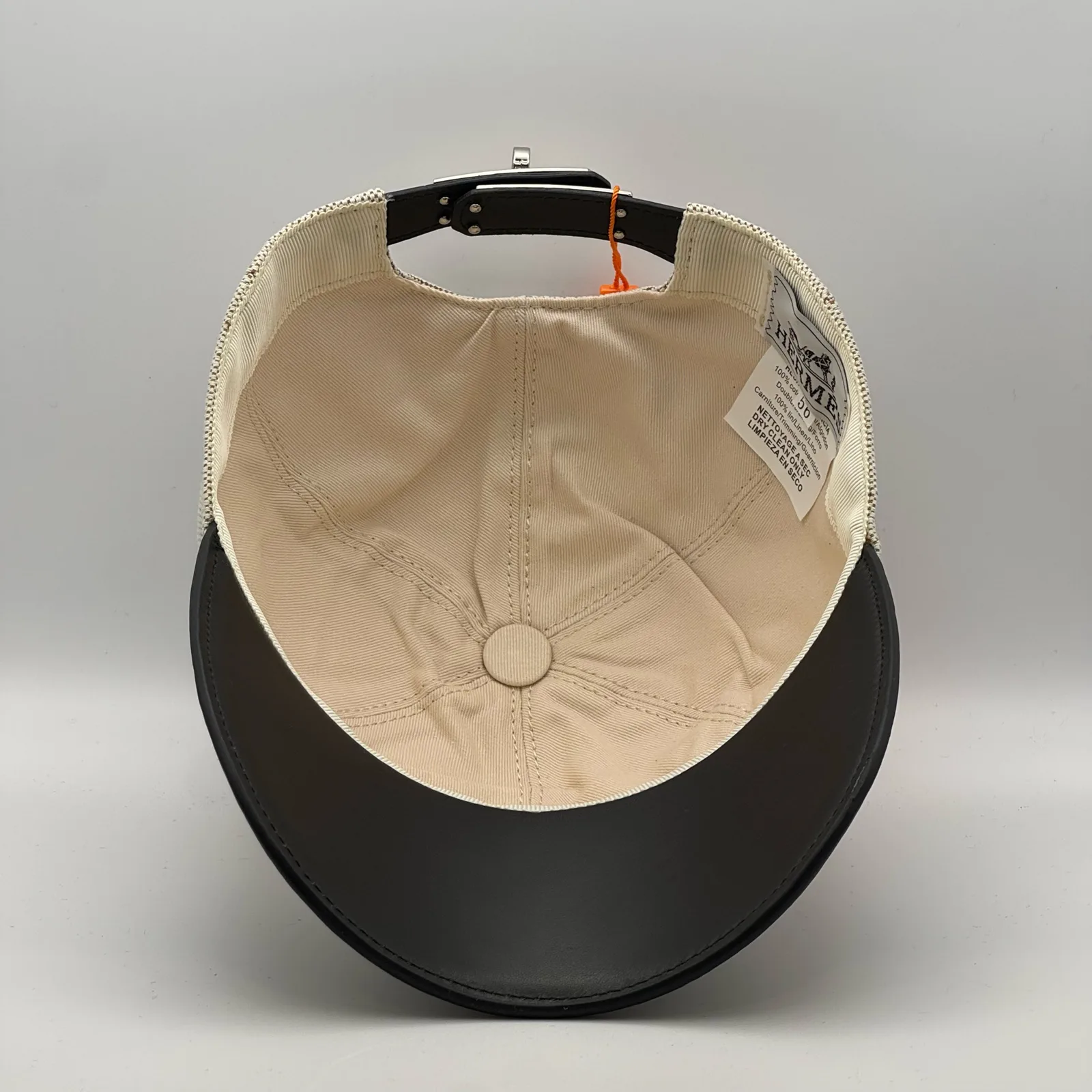 Hermès canvas cap, underside view showing the cream interior lining and black brim.