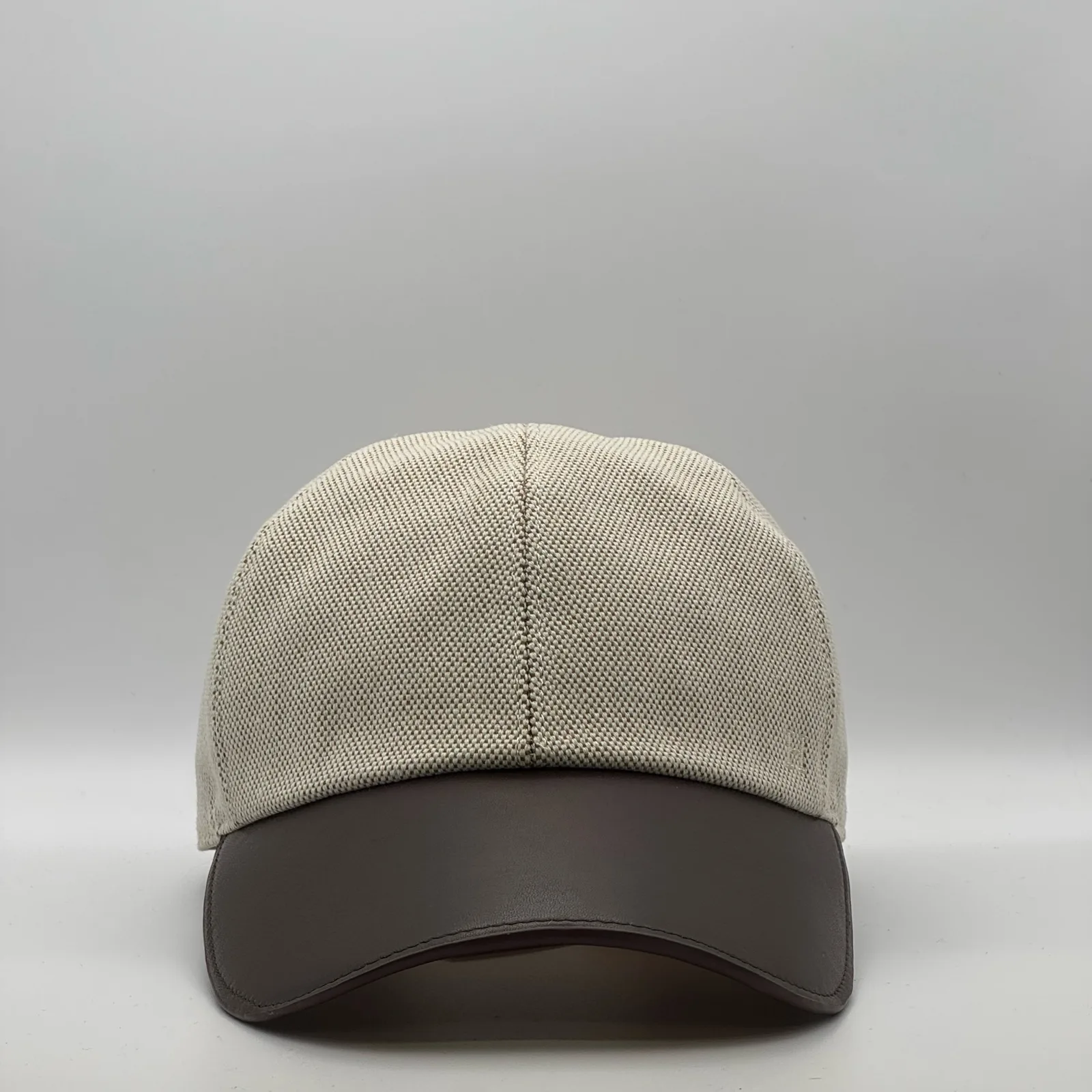 Hermès canvas cap, front view in oatmeal weave with a dark brown leather brim.