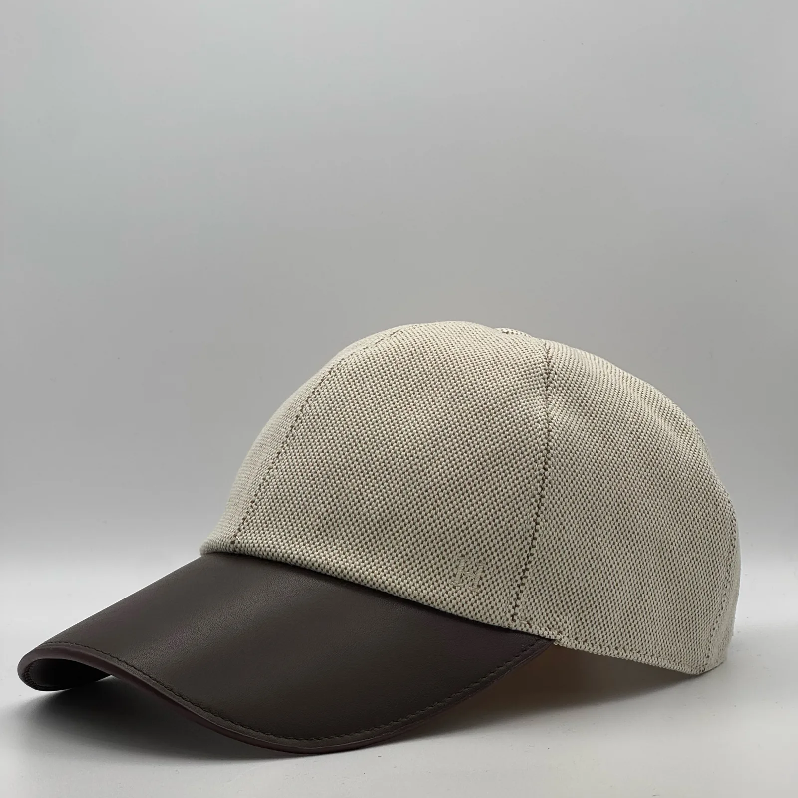 Hermès canvas cap, side profile in woven canvas with a dark brown leather brim.