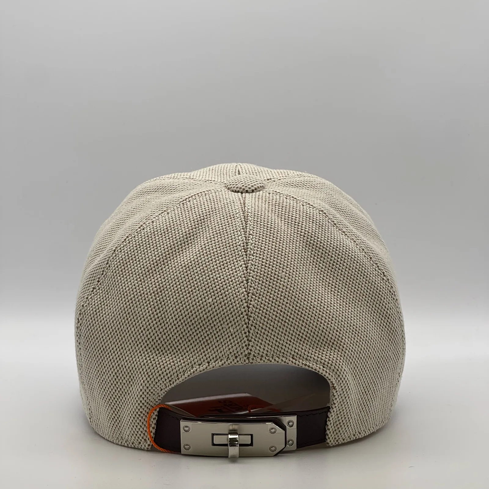 Hermès canvas cap, back view showing the dark brown leather strap and metal buckle closure.