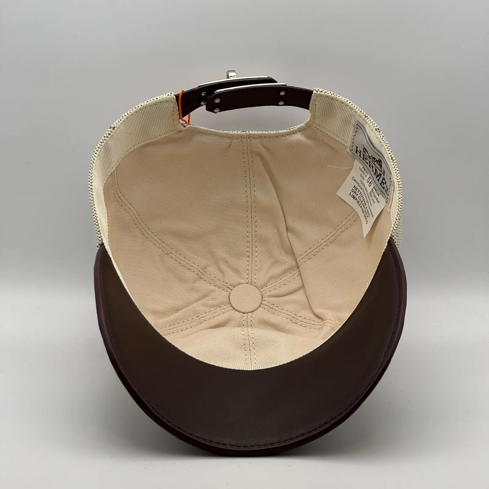 Hermès canvas cap, underside view showing the cream interior lining and dark brown brim.