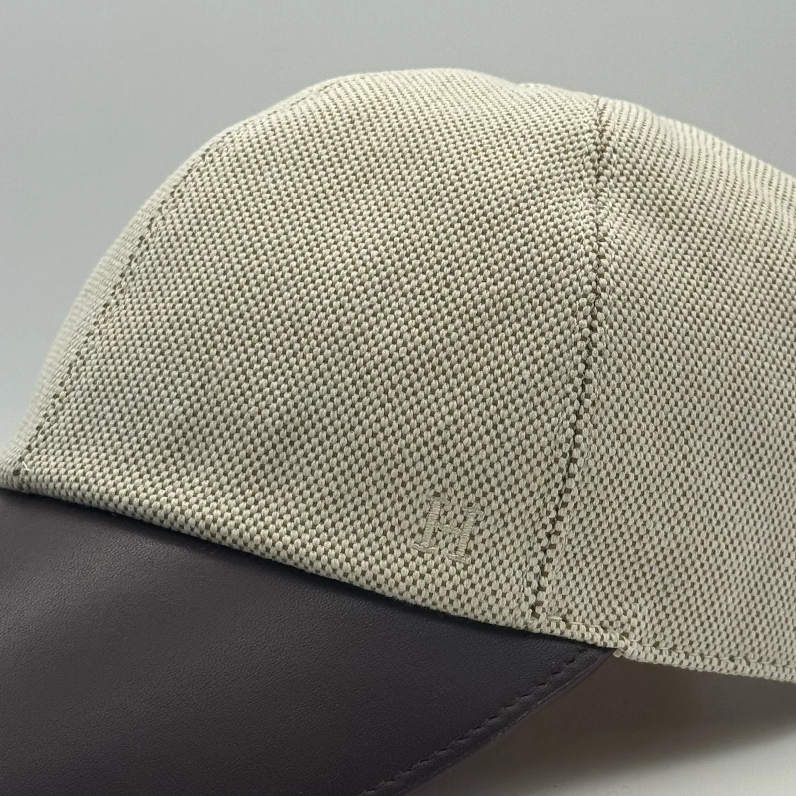 Close-up of the dark brown leather brim meeting the woven canvas crown, with a small tone-on-tone logo.
