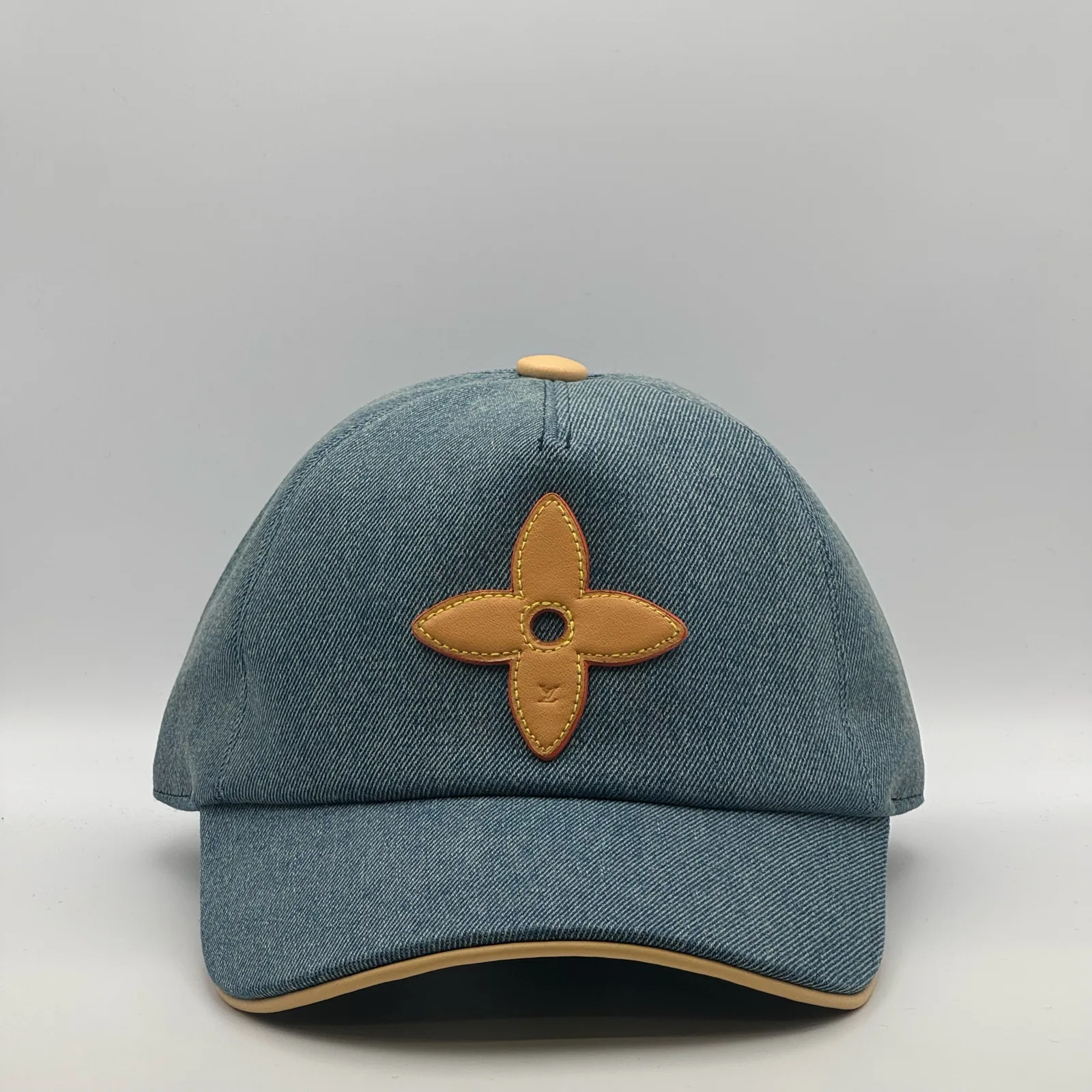 Blue denim Louis Vuitton Flower cap, front view showing the leather flower emblem.