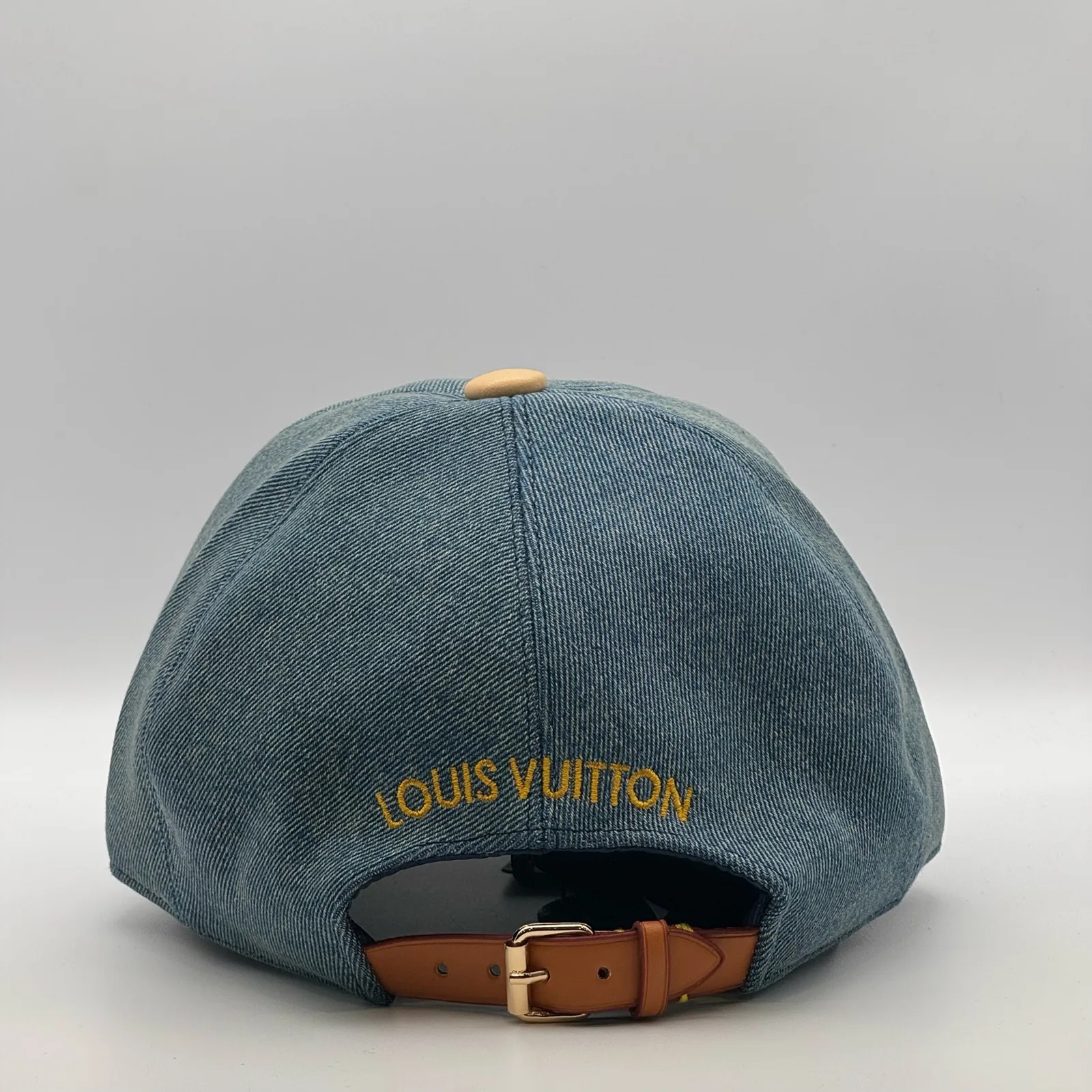 Blue denim flower cap, back view showing the embroidered wordmark and strap.
