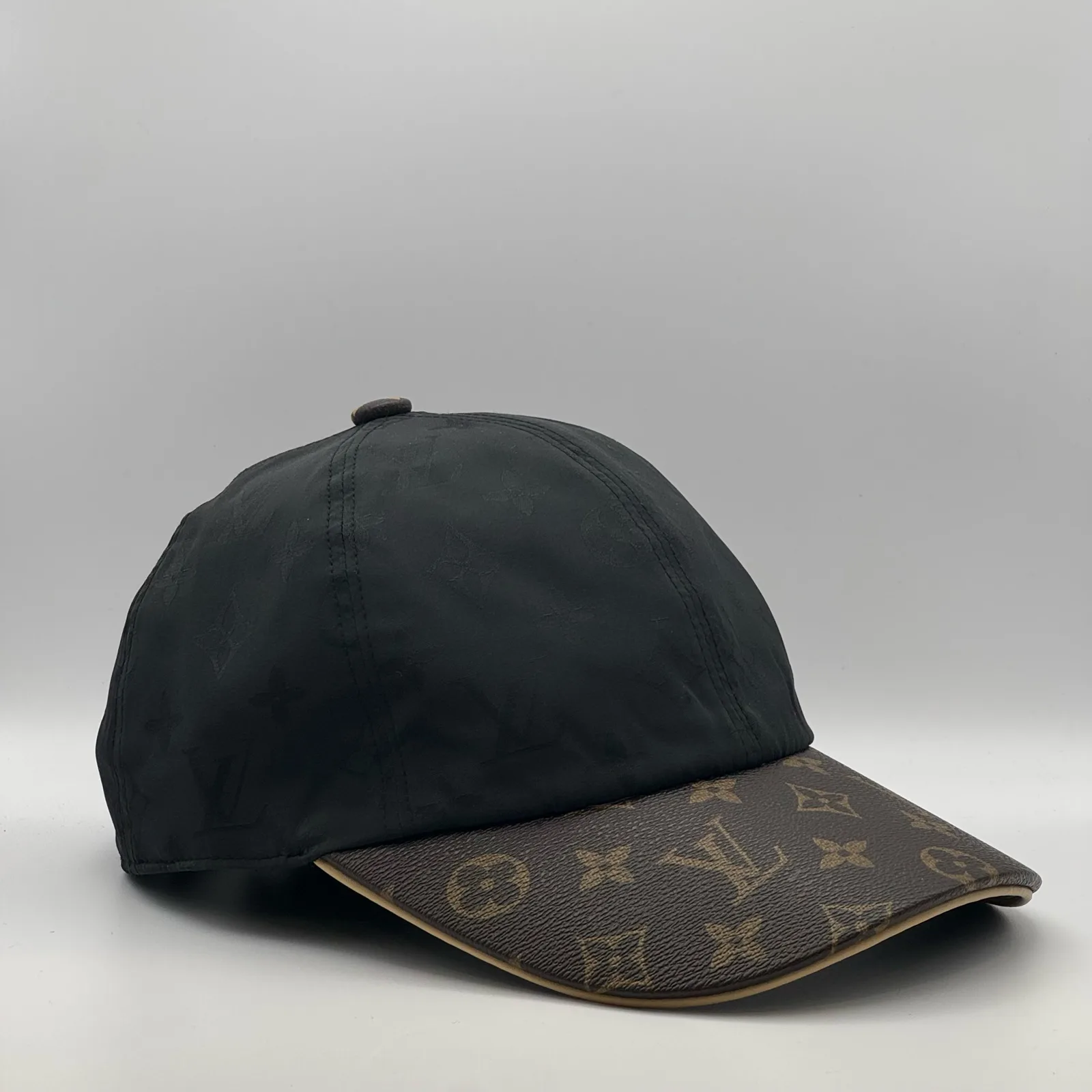 Black monogram brim cap, side profile view.