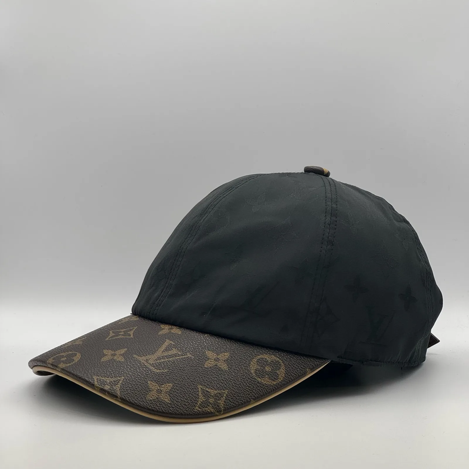 Black monogram brim cap, angled side view.