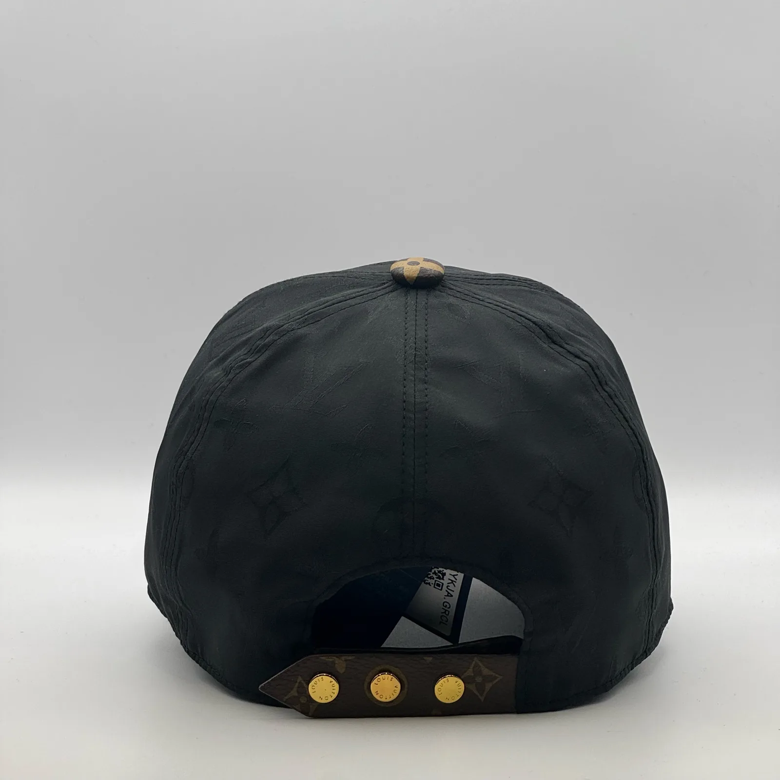 Black monogram brim cap, back view showing the gold snap-stud closure.