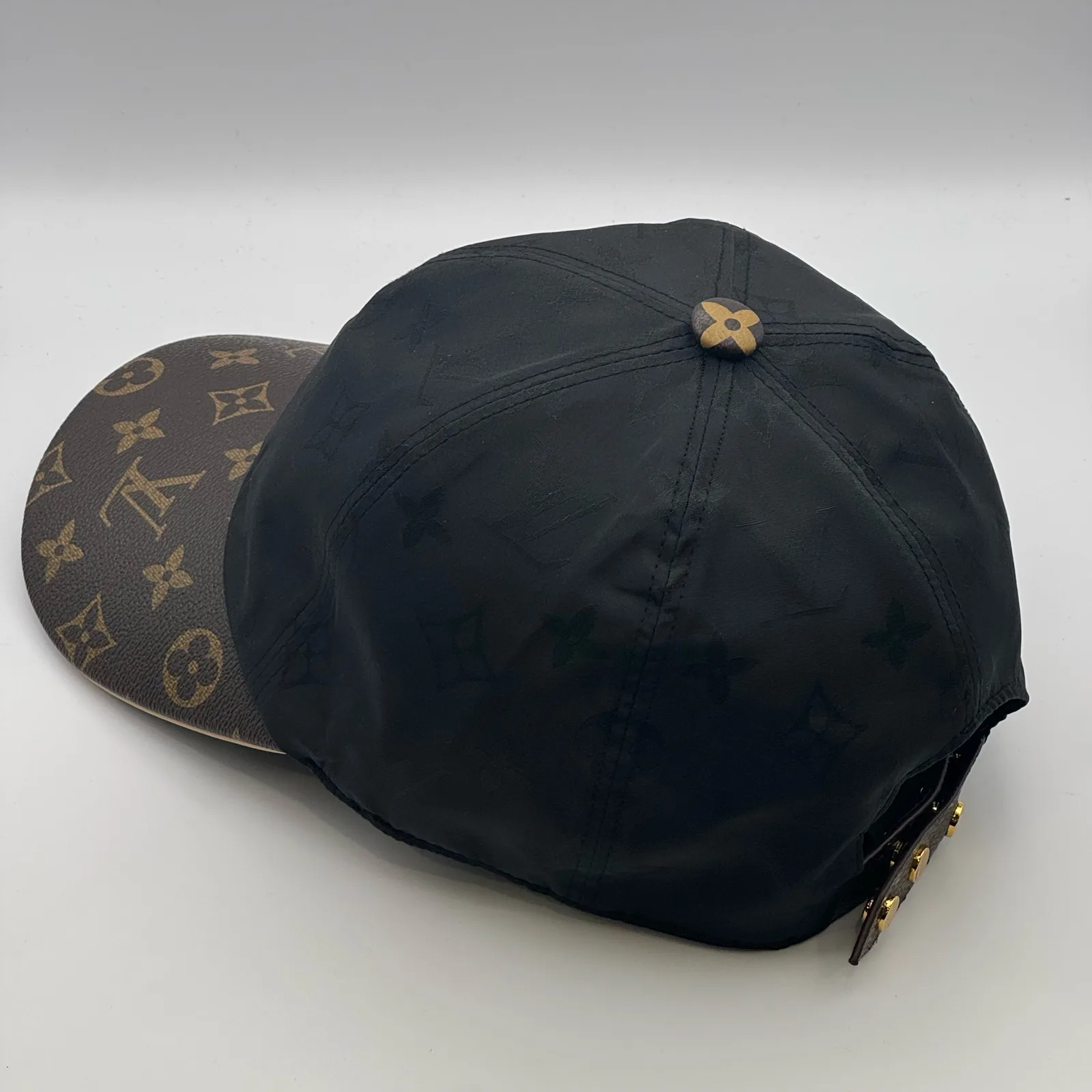Black monogram brim cap, three-quarter back view.