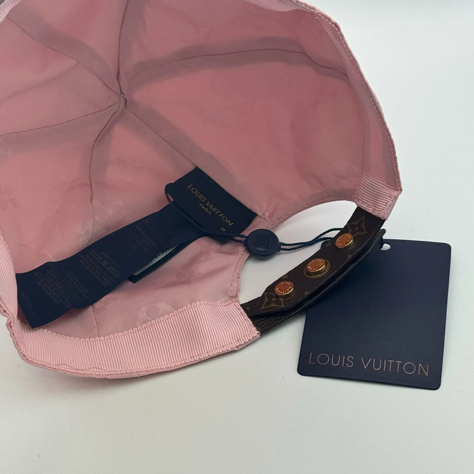 Inside view of the pink cap with the strap and brand tags visible.