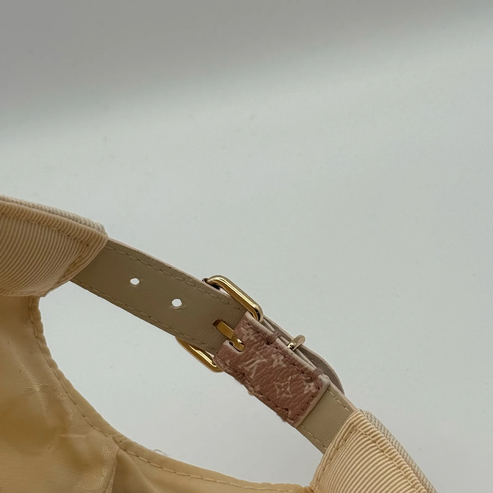 Close-up of the leather strap buckle on the beige flower cap.