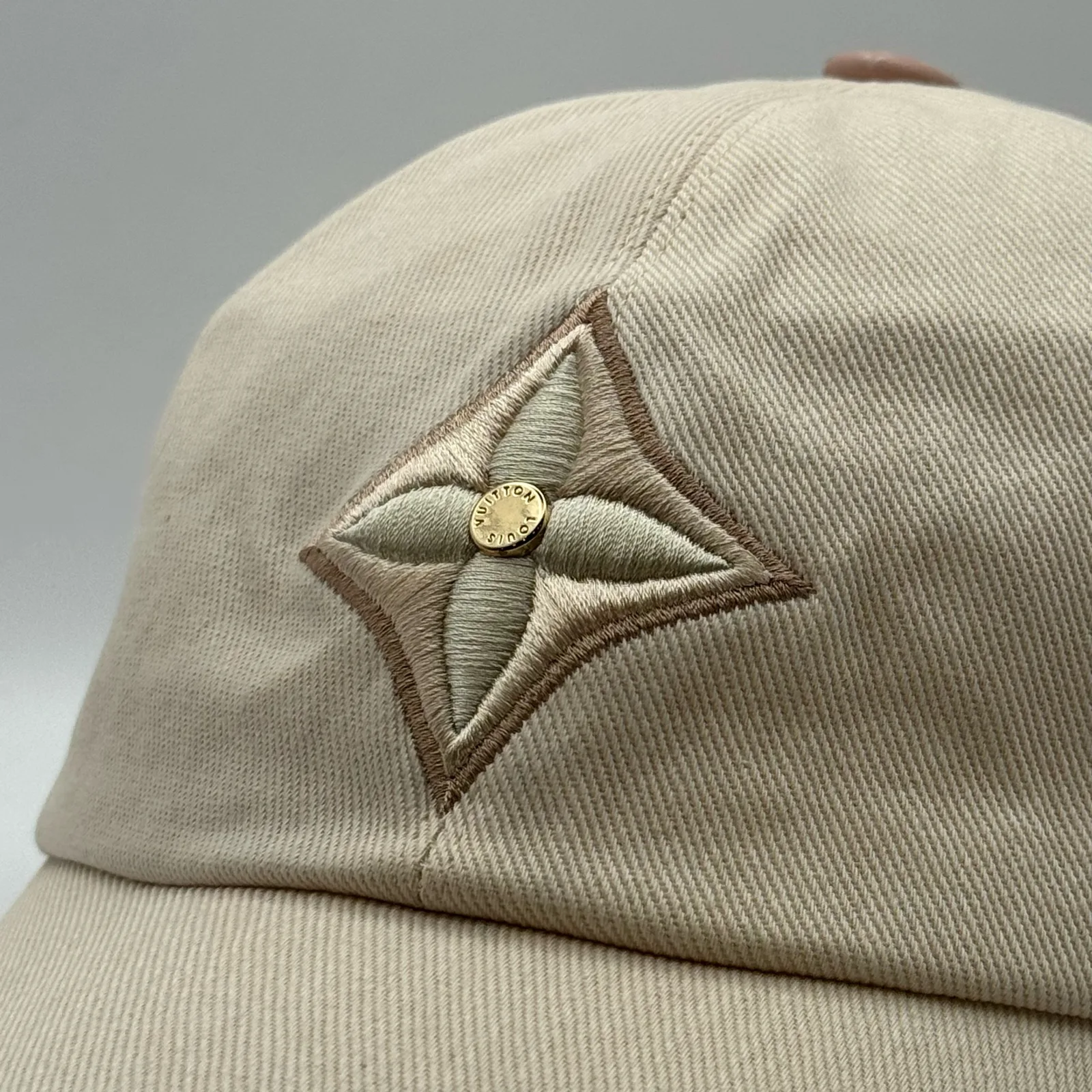 Close-up of the tonal flower emblem with its gold-tone centre stud.